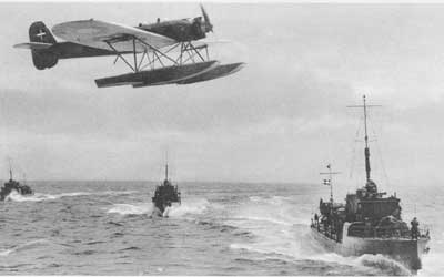 A low flying H.M. II (HEINKEL H.E.8) passing three DRAGEN Class torpedo boats